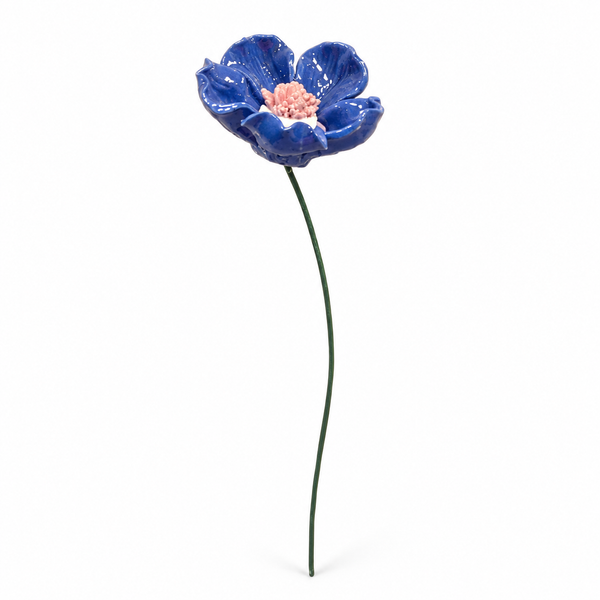 Flor de cerámica azul con centro rosa y tallo verde sobre fondo blanco