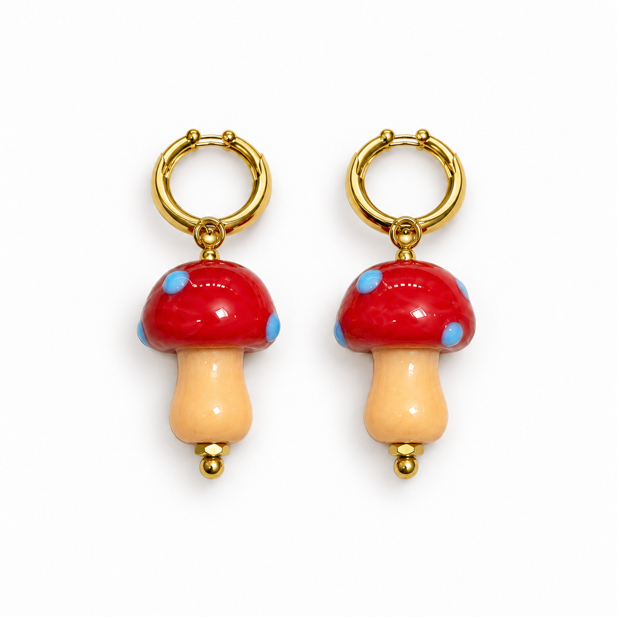 Mini pendientes de aro dorado con seta de vidrio roja y puntos azules, fondo blanco