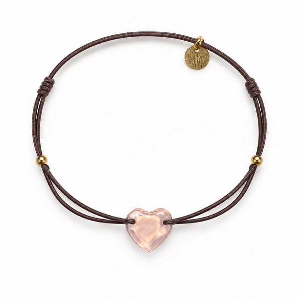 Pulsera marrón con corazón rosa sobre fondo blanco